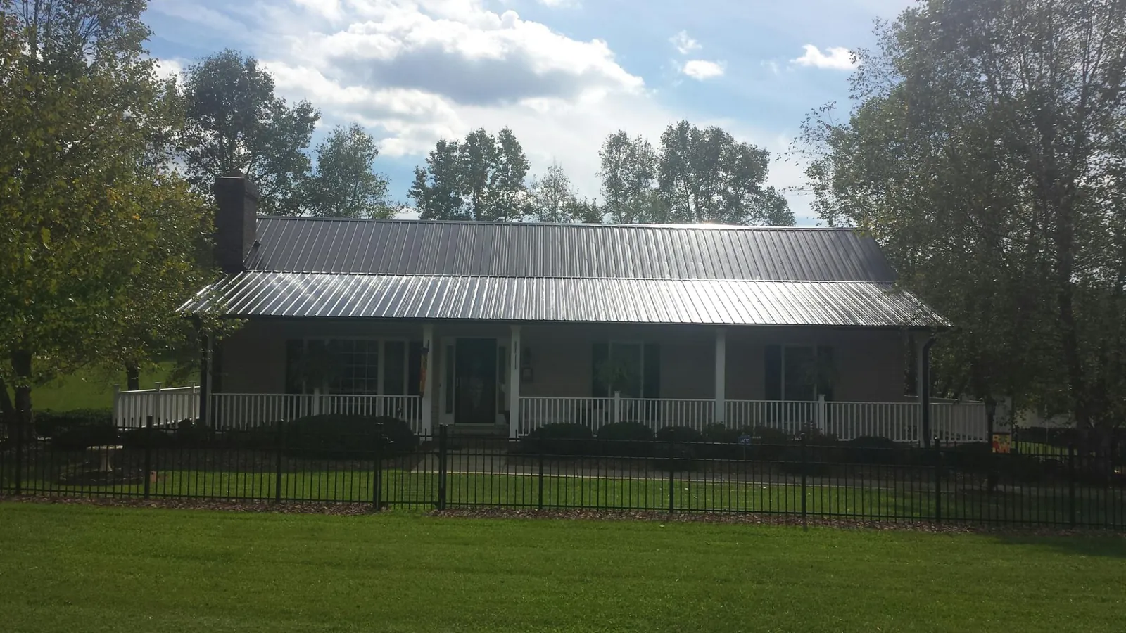 Gray metal roof on a brick ranch with a full width front porch — Gutter Guard Installation work by our crew in Cordova